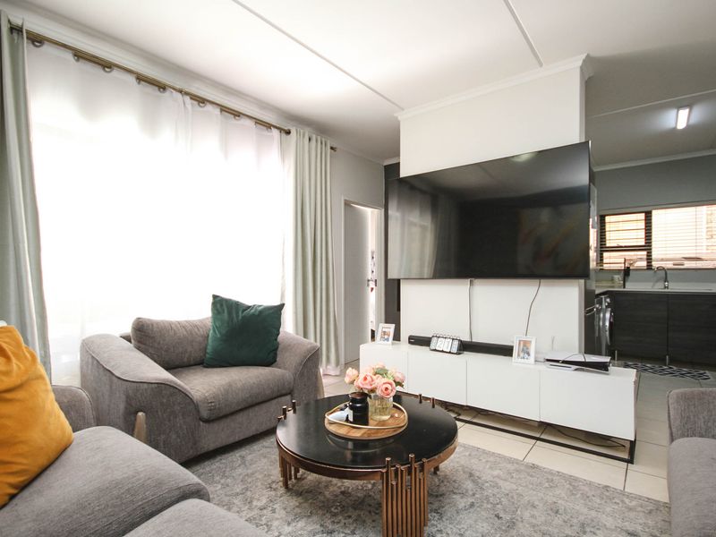 An open-plan living area featuring tiled floors and a seamless transition into a functional kitchen space with built-in cabinetry.