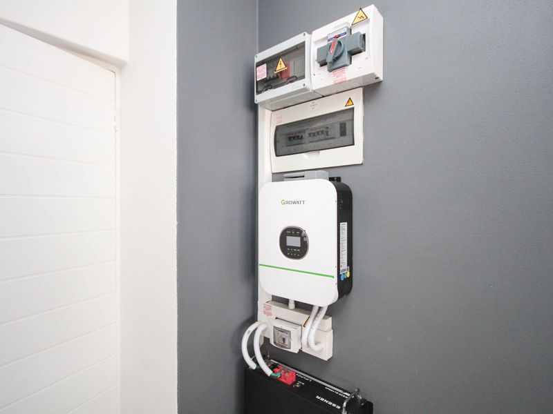 Wall-mounted solar power system featuring a Growatt inverter, battery storage unit, and electrical distribution board.