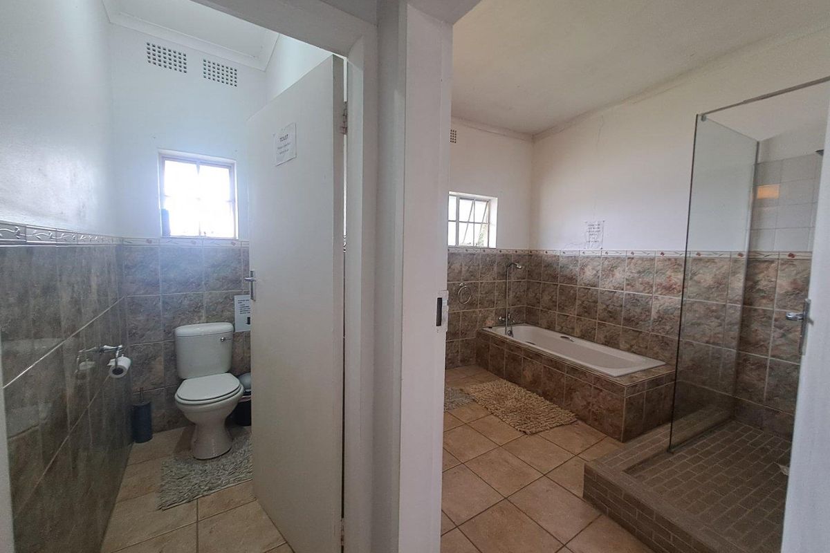 A functional bathroom featuring a separate toilet, a built-in bathtub, and a glass-enclosed shower with neutral tiled finishes.