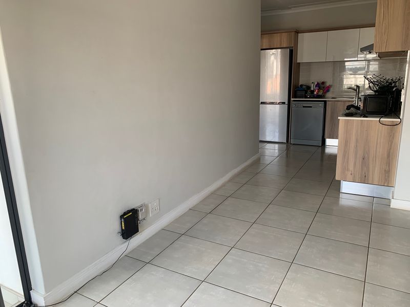 An open-plan living area featuring tiled flooring and a modern kitchen with built-in cabinetry and integrated appliances.