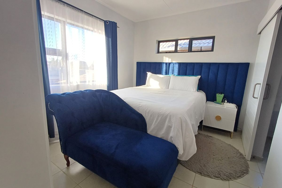 A well-maintained bedroom featuring tiled flooring, a large window, and a sliding door, providing a bright and comfortable living space.