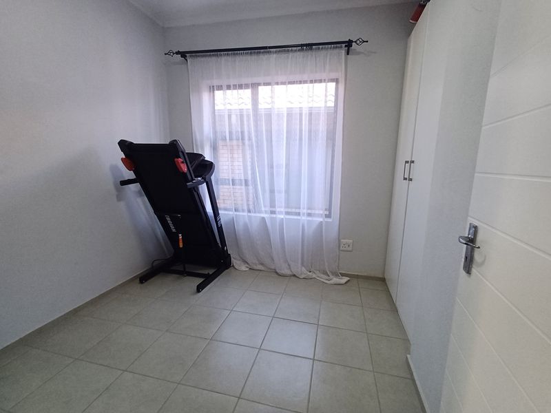 A bedroom featuring neutral tiled flooring and built-in cupboards, providing a clean and functional space.