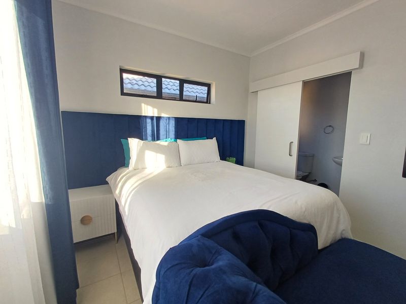 A well-maintained bedroom featuring a modern sliding door leading to an en-suite bathroom, tiled flooring, and a horizontal window for natural light.