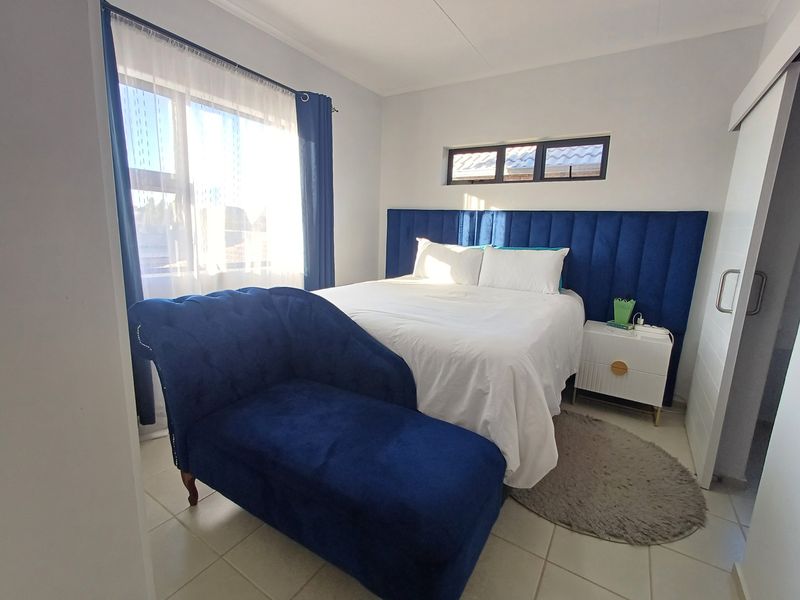 A well-maintained bedroom featuring tiled flooring, a large window, and a sliding door, providing a bright and comfortable living space.