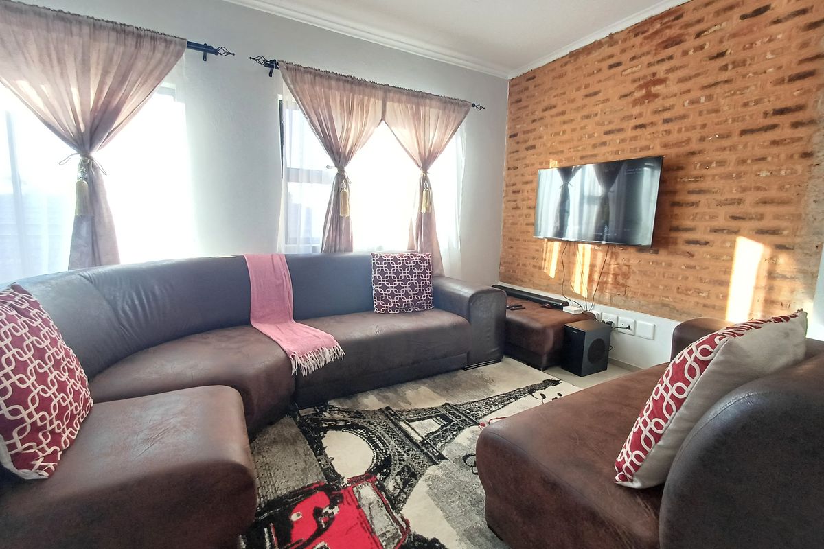 A comfortable living room featuring a distinctive exposed brick feature wall and coved ceiling details.
