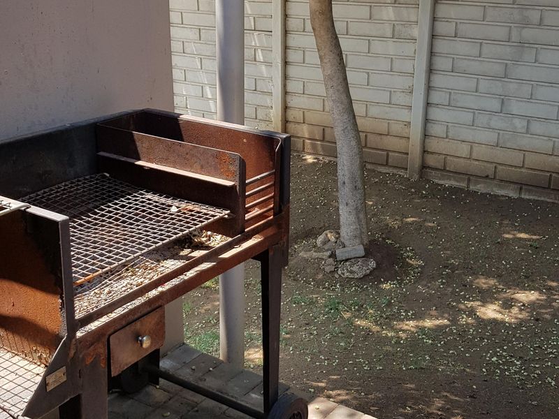 A rear outdoor area featuring a paved patio space and a boundary wall, suitable for garden development or outdoor entertainment.