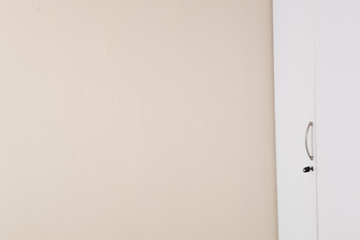 A simple bedroom interior featuring a white built-in wardrobe and neutral wall finishes.