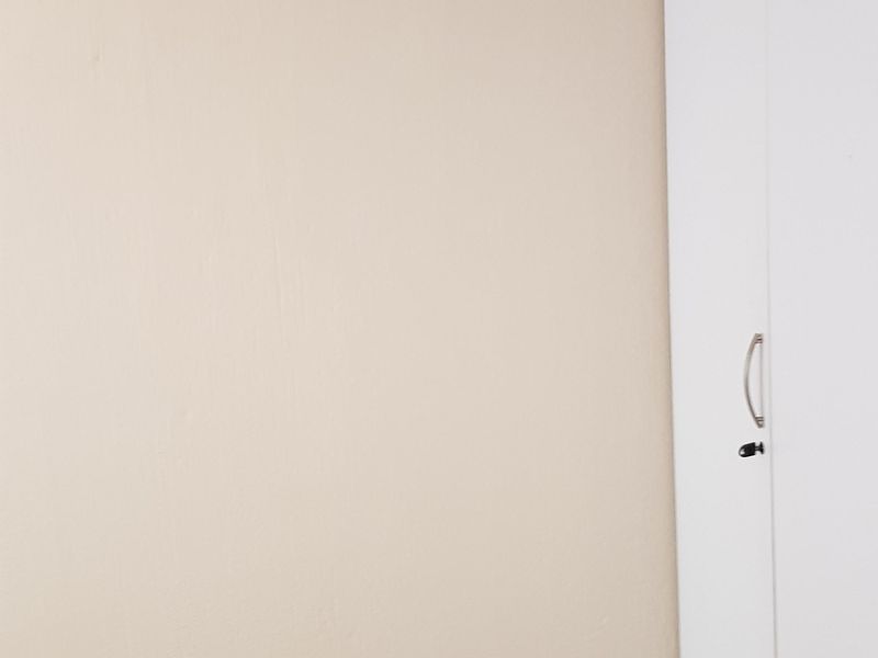 A simple bedroom interior featuring a white built-in wardrobe and neutral wall finishes.