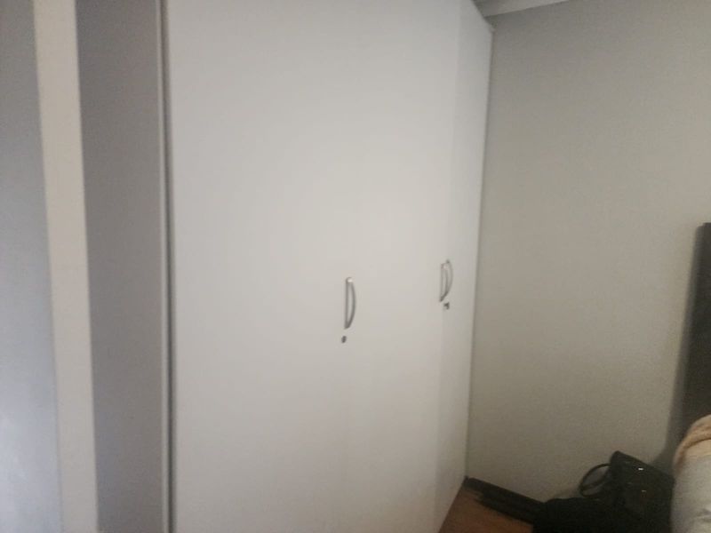A bedroom featuring a white built-in wardrobe with silver handles.