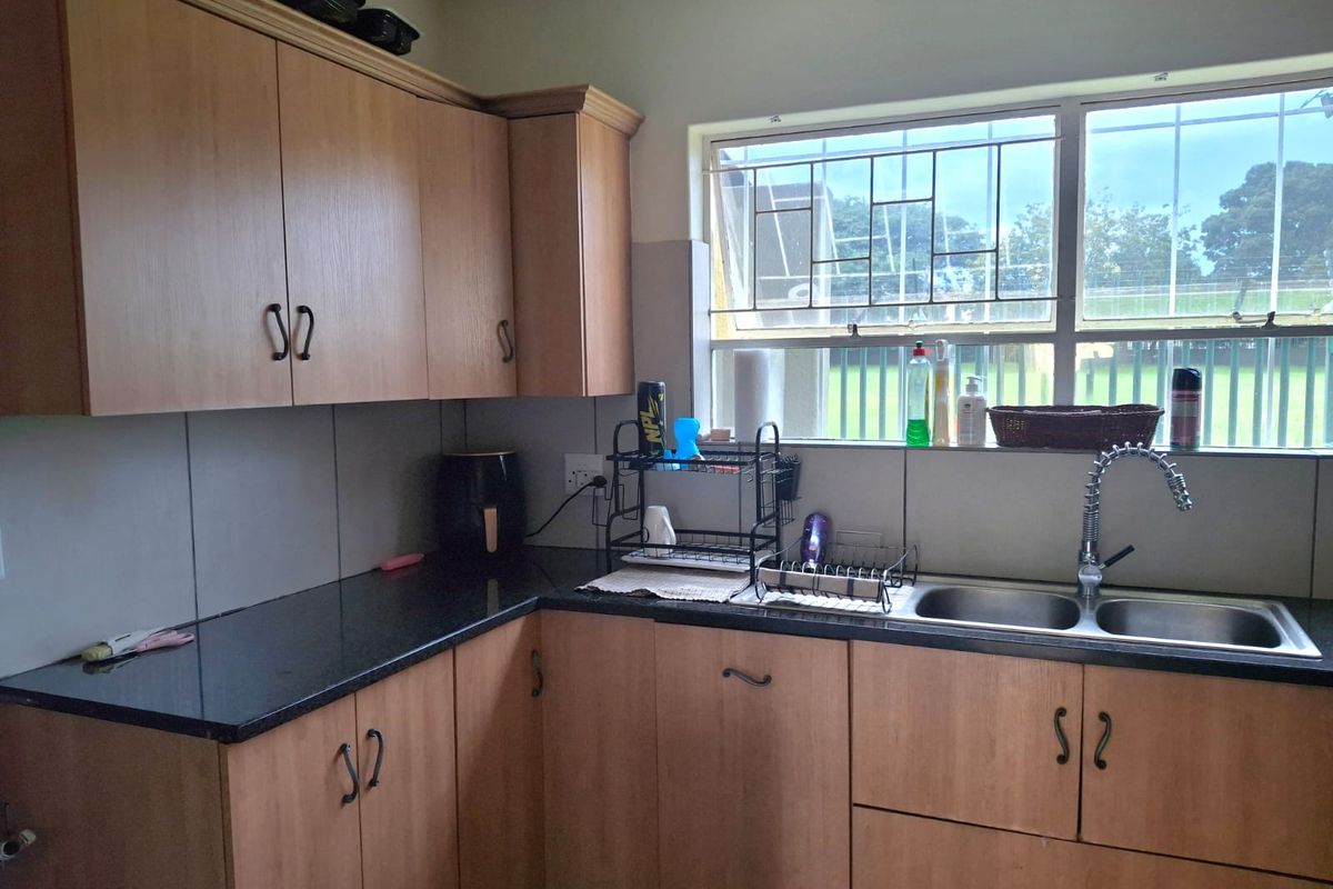 A functional kitchen featuring laminate cabinetry, granite countertops, and a double bowl stainless steel sink with a gooseneck faucet.