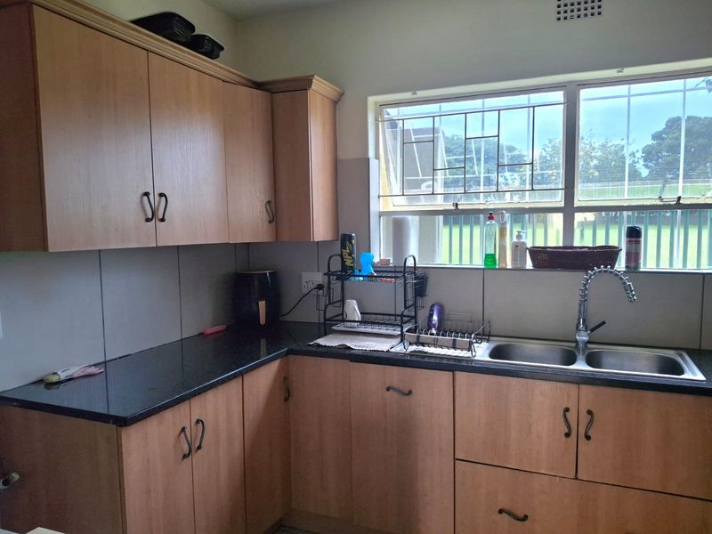 A functional kitchen featuring laminate cabinetry, granite countertops, and a double bowl stainless steel sink with a gooseneck faucet.