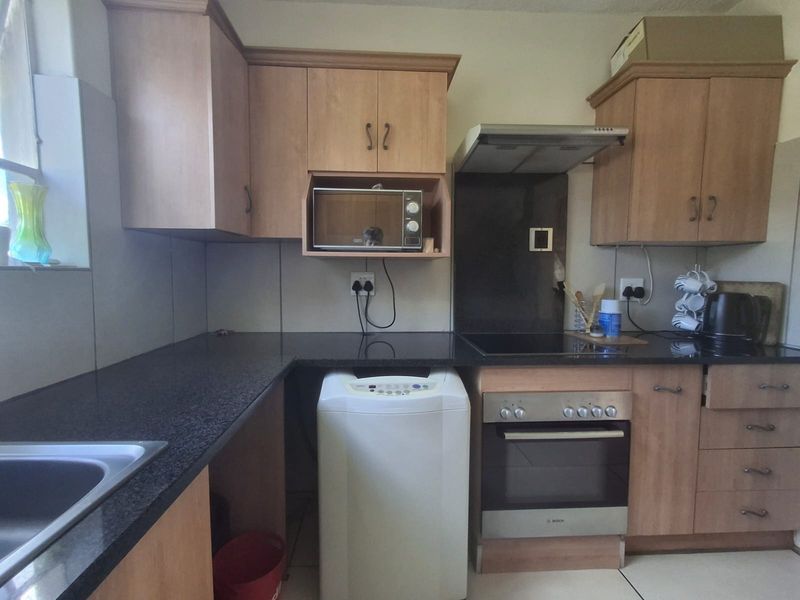 A functional kitchen featuring laminate cabinetry, granite countertops, a built-in oven with extractor fan, and tiled flooring.