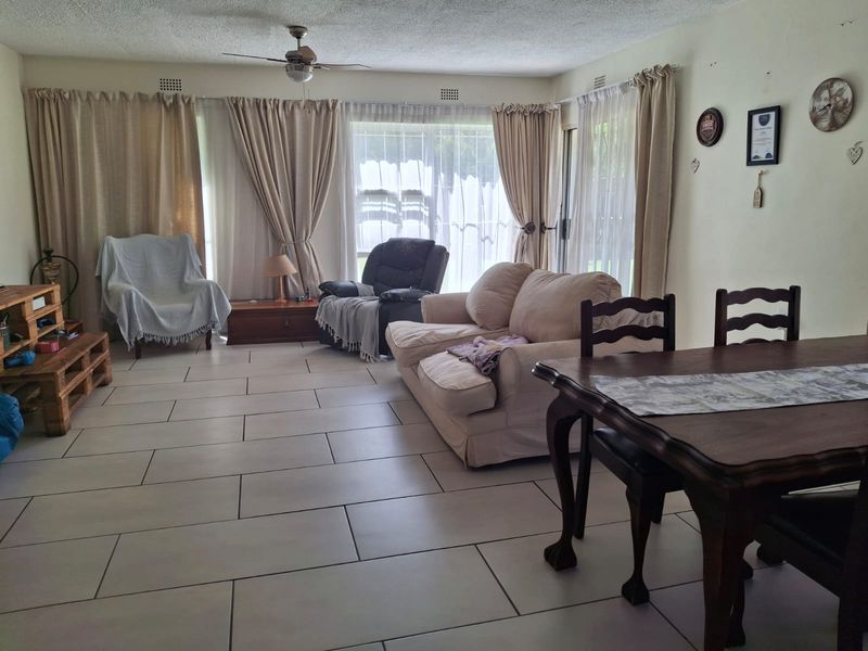 Spacious open-plan living and dining area featuring neutral tiled flooring, a ceiling fan, and large sliding glass doors providing access to the exterior.
