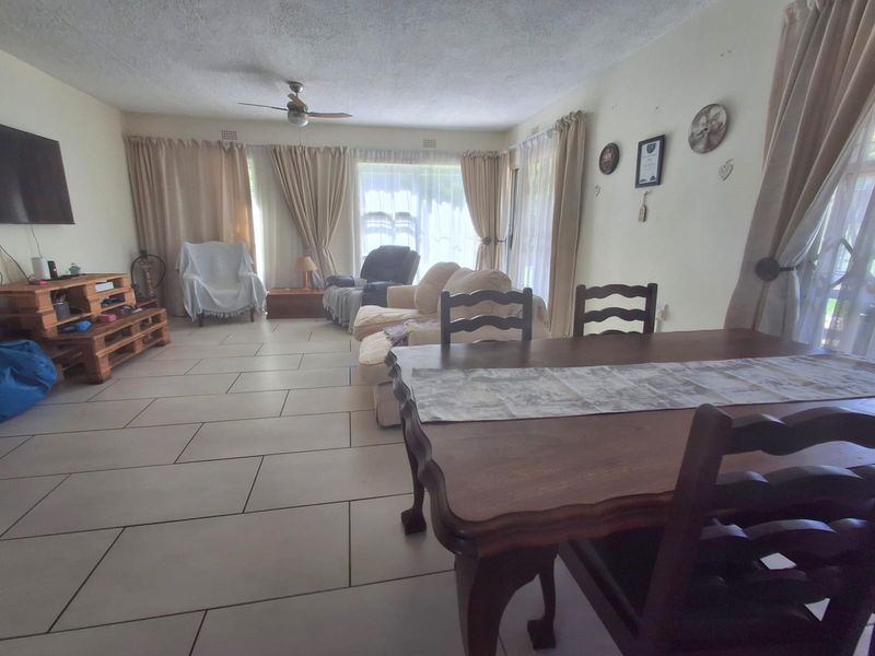 Spacious open-plan living and dining area featuring large sliding glass doors, tiled flooring, and a ceiling fan, offering a bright and functional layout.