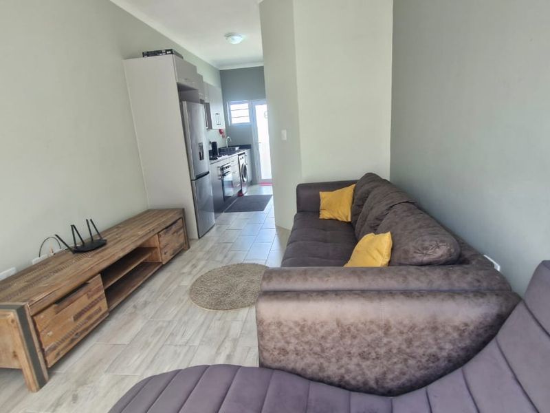 Open-plan living area featuring tiled flooring and a compact kitchen with built-in cabinetry, providing a functional and connected layout.