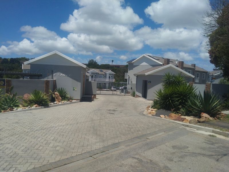 Front entrance view of the apartment complex featuring a paved driveway, secure gated access, and well-maintained exterior building facades.