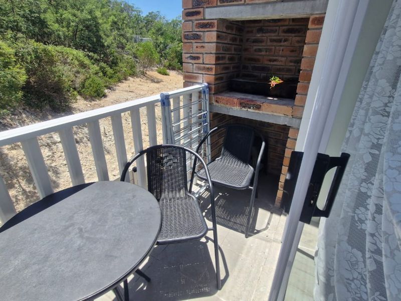A compact balcony featuring a built-in brick braai and a white balustrade, offering an outdoor space for relaxation.