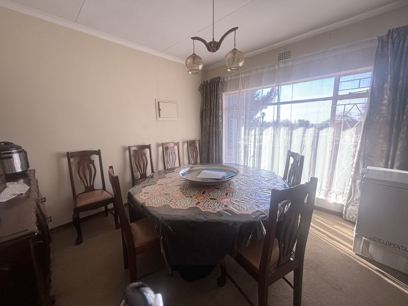 A dining room featuring a large window that allows for natural light, finished with a ceiling light fixture and standard wall finishes.