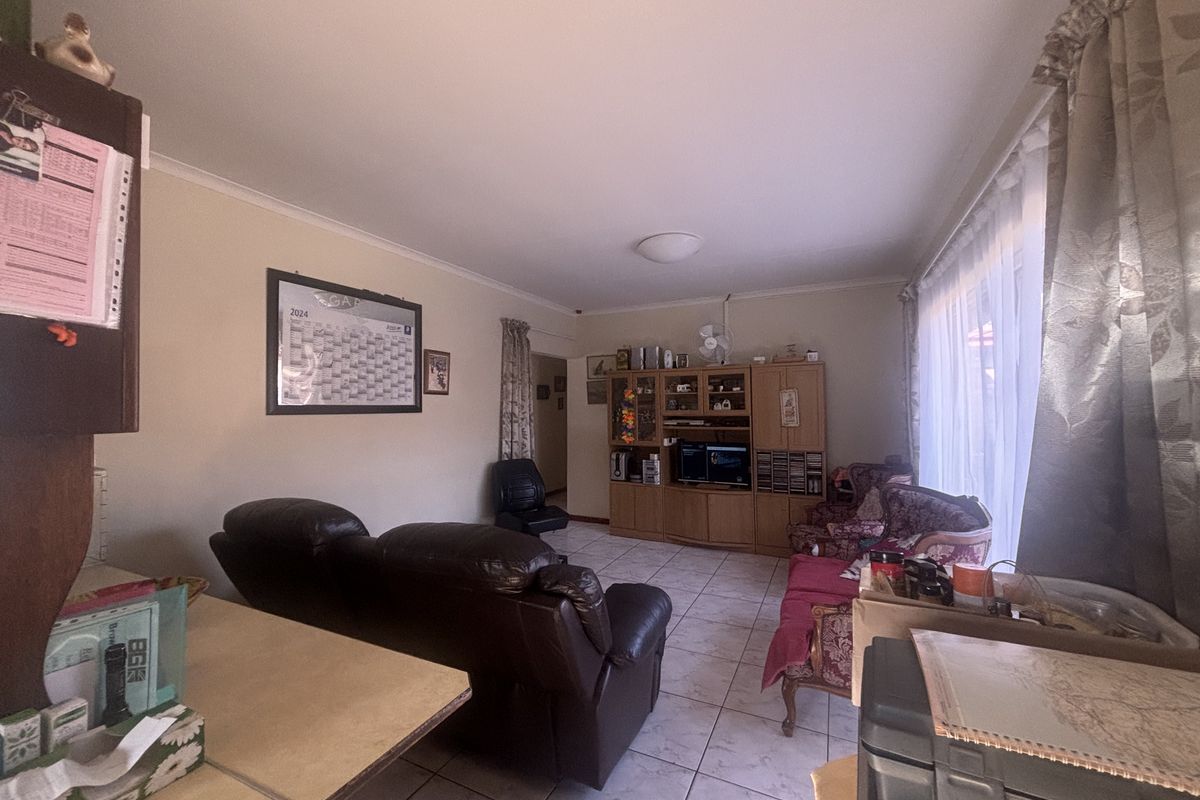 A living room featuring tiled flooring and neutral wall finishes, offering a functional space with natural light from the side window.