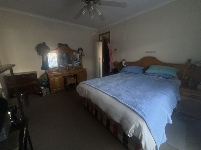 A standard bedroom featuring a ceiling fan and coving, providing a functional space for rest.