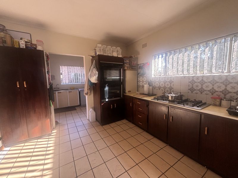 A functional kitchen featuring built-in cabinetry, a gas hob, and an integrated oven, with a separate scullery area visible through the doorway.
