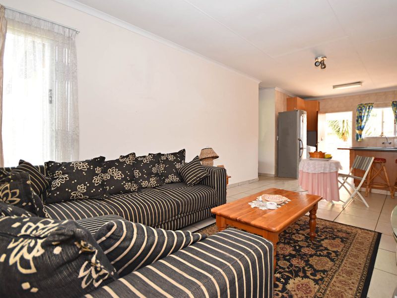 Open-plan living and kitchen area featuring tiled flooring, a breakfast bar, and direct access to the exterior.