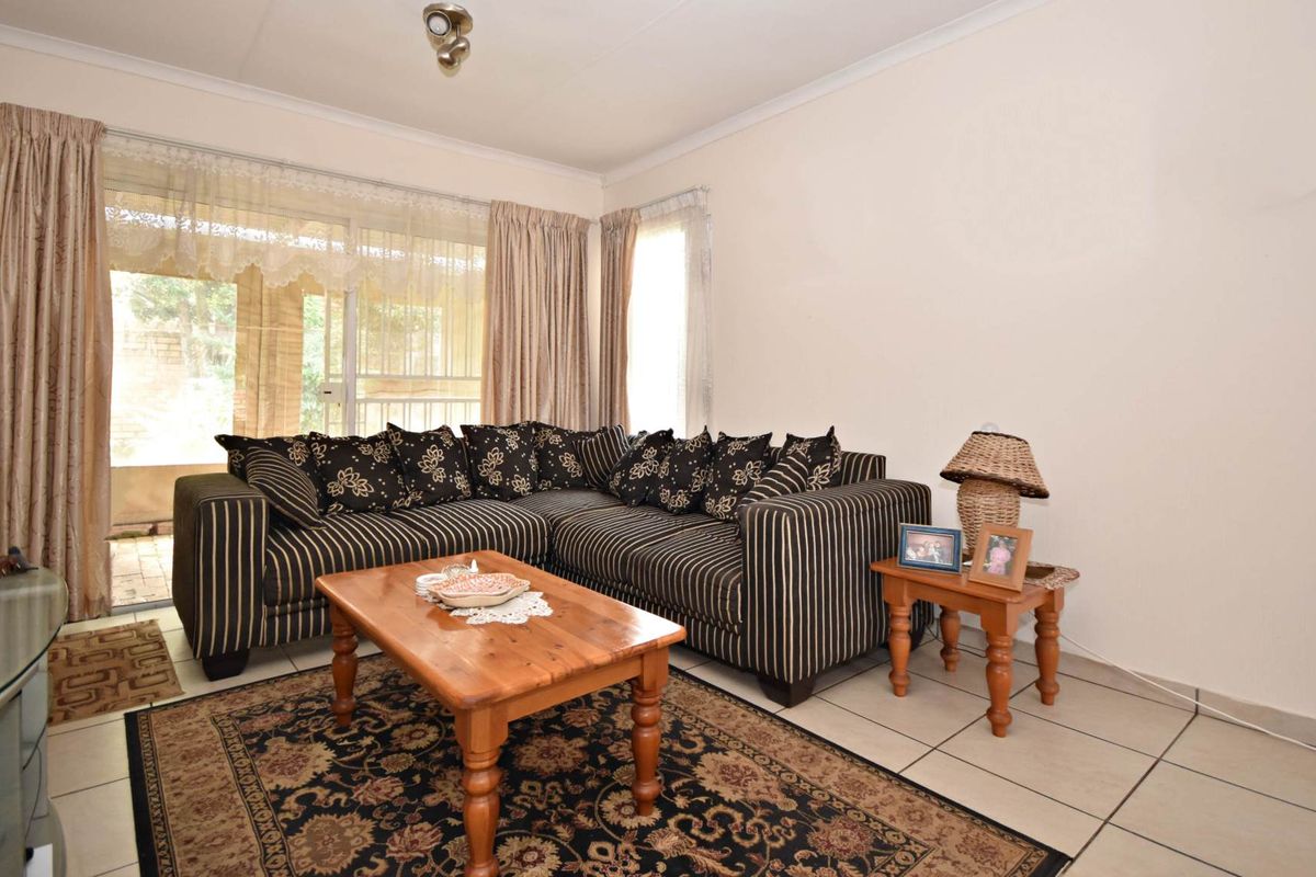 A living room featuring neutral tiled flooring and a sliding glass door providing access to the outdoor area.