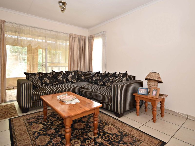 A living room featuring neutral tiled flooring and a sliding glass door providing access to the outdoor area.