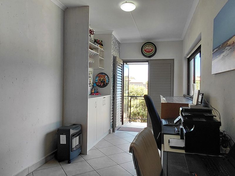 A functional home office space featuring built-in cabinetry, tiled flooring, and direct access to an outdoor balcony area.