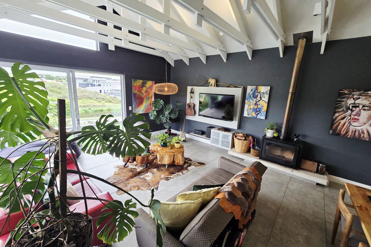 Spacious living room featuring high vaulted ceilings with exposed rafters, a modern freestanding fireplace, and large sliding doors opening to an outdoor view.