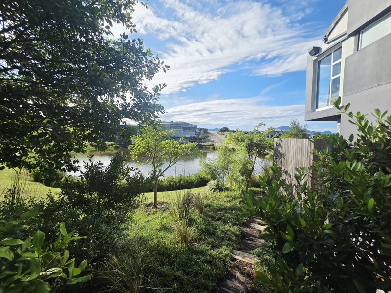 A scenic view of a tranquil pond and landscaped garden area, framed by modern architectural elements and lush greenery.