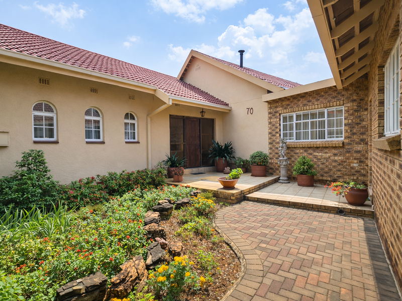 A well-maintained front entrance featuring a brick facade, arched windows, and a paved walkway leading to a covered entryway.