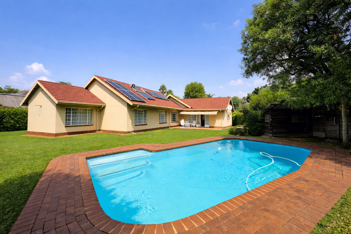 Rear view of the property featuring a well-maintained swimming pool, brick paved surround, solar panels on the tiled roof, and a spacious garden.