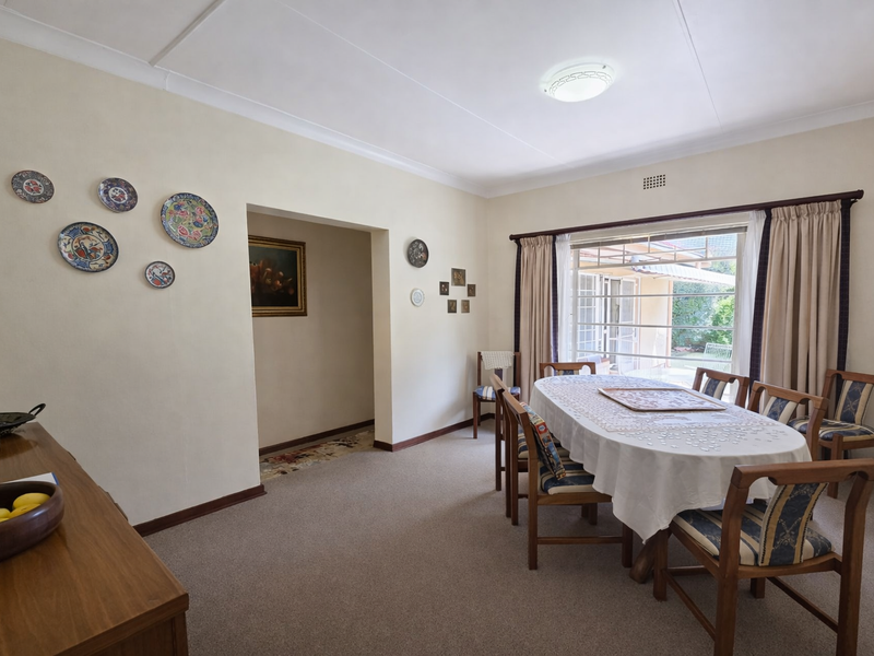 A dining room featuring carpeted flooring, coved ceilings, and a large window providing natural light and access to the outdoor area.