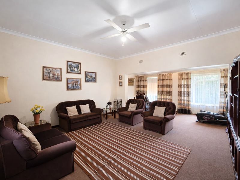 Spacious living room featuring neutral walls, carpeted flooring, and a central ceiling fan, offering a comfortable and traditional layout.