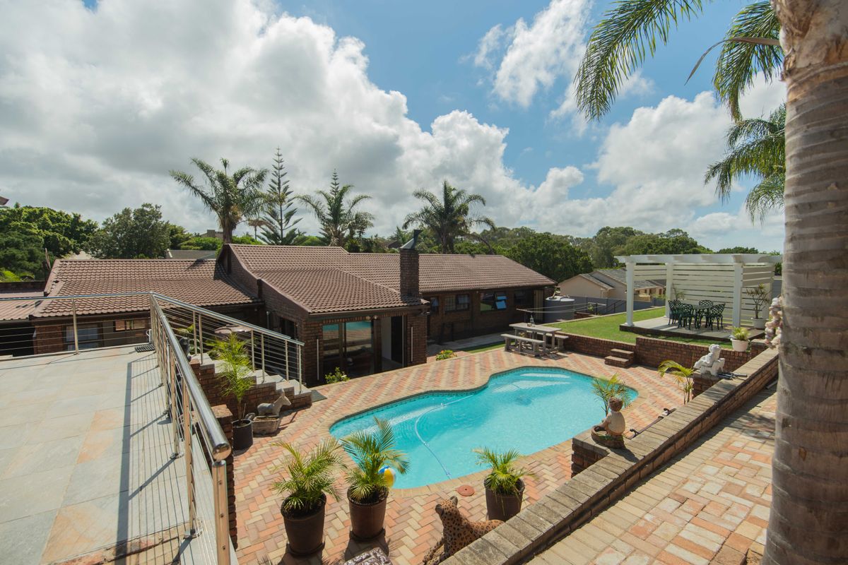 Rear exterior view featuring a swimming pool, brick paved patio area, raised garden beds, and a pergola, set against a well-maintained brick house.