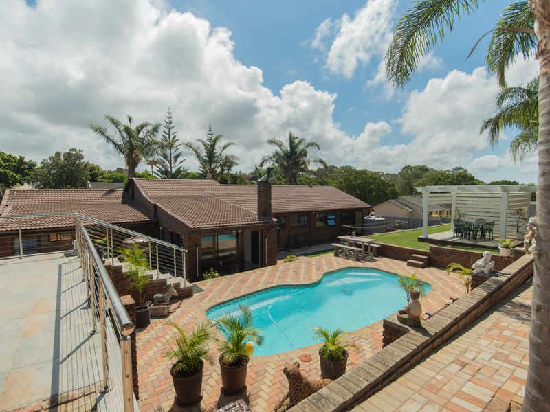Rear exterior view featuring a swimming pool, brick paved patio area, raised garden beds, and a pergola, set against a well-maintained brick house.
