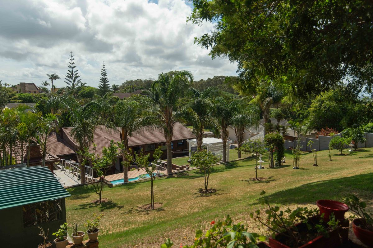 Elevated view of the property grounds featuring a swimming pool, pergola, and well-maintained garden area with mature palm trees.