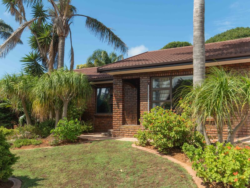 A well-maintained face brick house exterior featuring a tiled roof, aluminium window frames, and a landscaped front garden with a paved walkway.