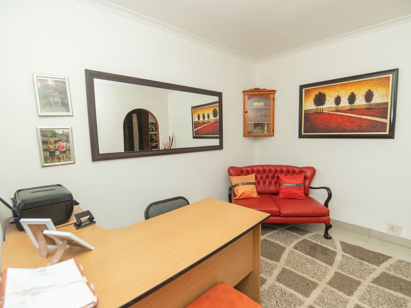 A functional home office space featuring tiled flooring, coved ceilings, and neutral wall finishes, providing a versatile area for work or study.