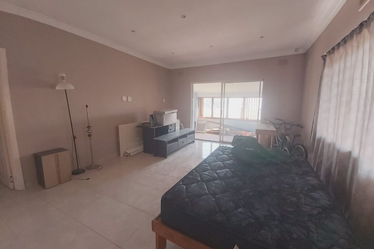 Spacious bedroom featuring tiled flooring, recessed downlighting, and a sliding glass door providing access to an adjoining patio area.