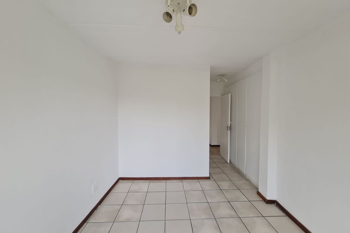 A clean, empty bedroom featuring neutral tiled flooring and built-in storage cupboards, offering a blank canvas for personalization.