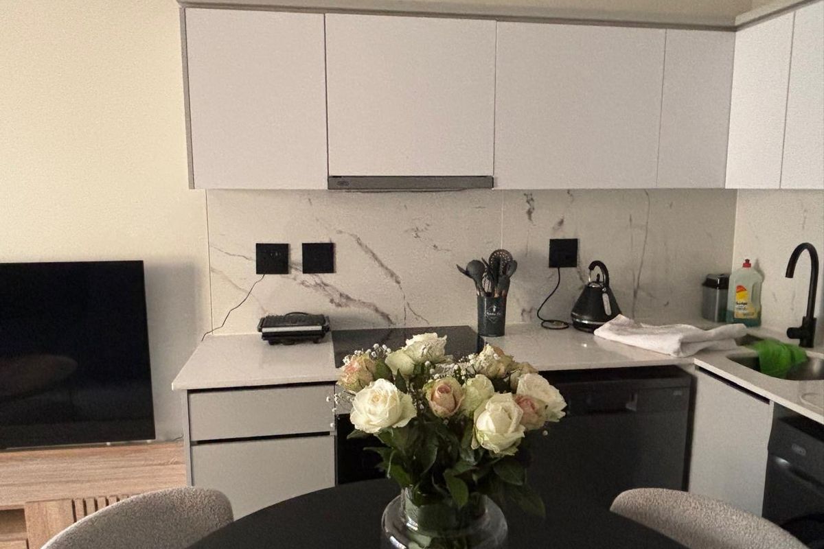 Modern kitchen featuring white cabinetry, marble-look splashback, quartz countertops, and integrated appliances, offering a clean and contemporary aesthetic.