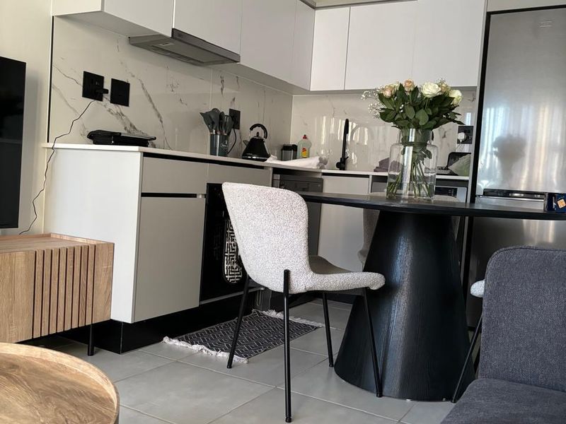 Modern open-plan kitchen featuring sleek white cabinetry, marble-look splashback, and tiled flooring, seamlessly integrated with the living area.