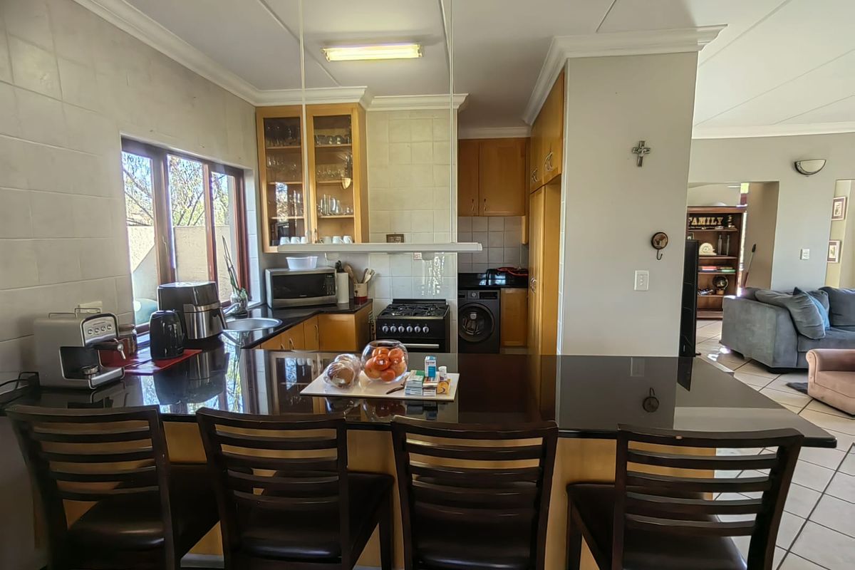 A functional kitchen featuring granite countertops, wooden cabinetry, a gas stove, and a breakfast bar, seamlessly flowing into the adjacent living area.