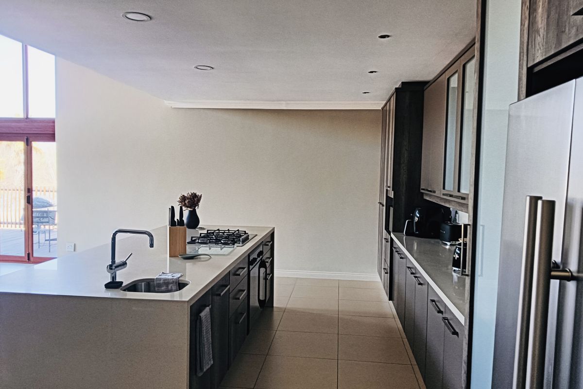 Modern kitchen featuring a central island with a gas hob and undermount sink, complemented by sleek cabinetry, stone countertops, and recessed lighting.