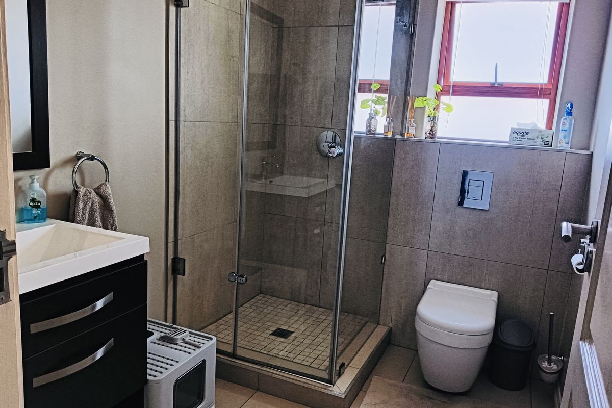 Modern bathroom featuring a glass-enclosed shower, wall-mounted toilet with concealed cistern, and a sleek vanity cabinet with basin.