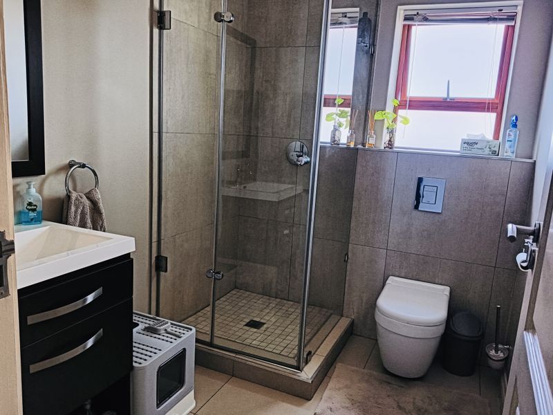 Modern bathroom featuring a glass-enclosed shower, wall-mounted toilet with concealed cistern, and a sleek vanity cabinet with basin.