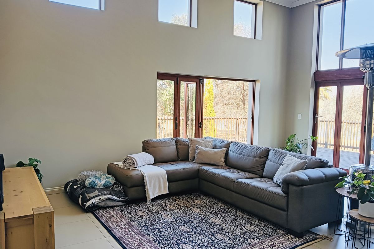 Spacious living room featuring high ceilings, clerestory windows, and large timber-framed folding doors that provide seamless access to the outdoor deck area.