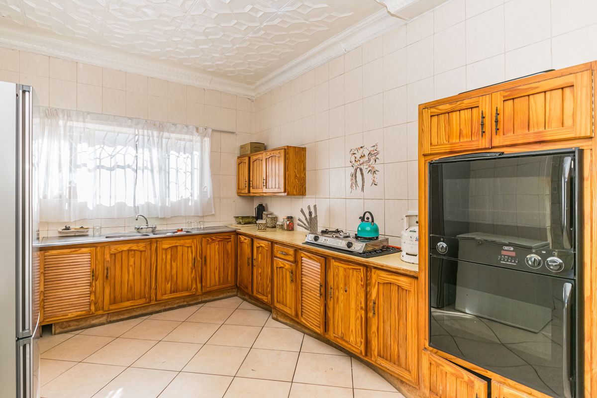 A functional kitchen featuring wooden cabinetry, a built-in oven, gas hob, and tiled finishes, offering a classic layout with potential for modern updates.